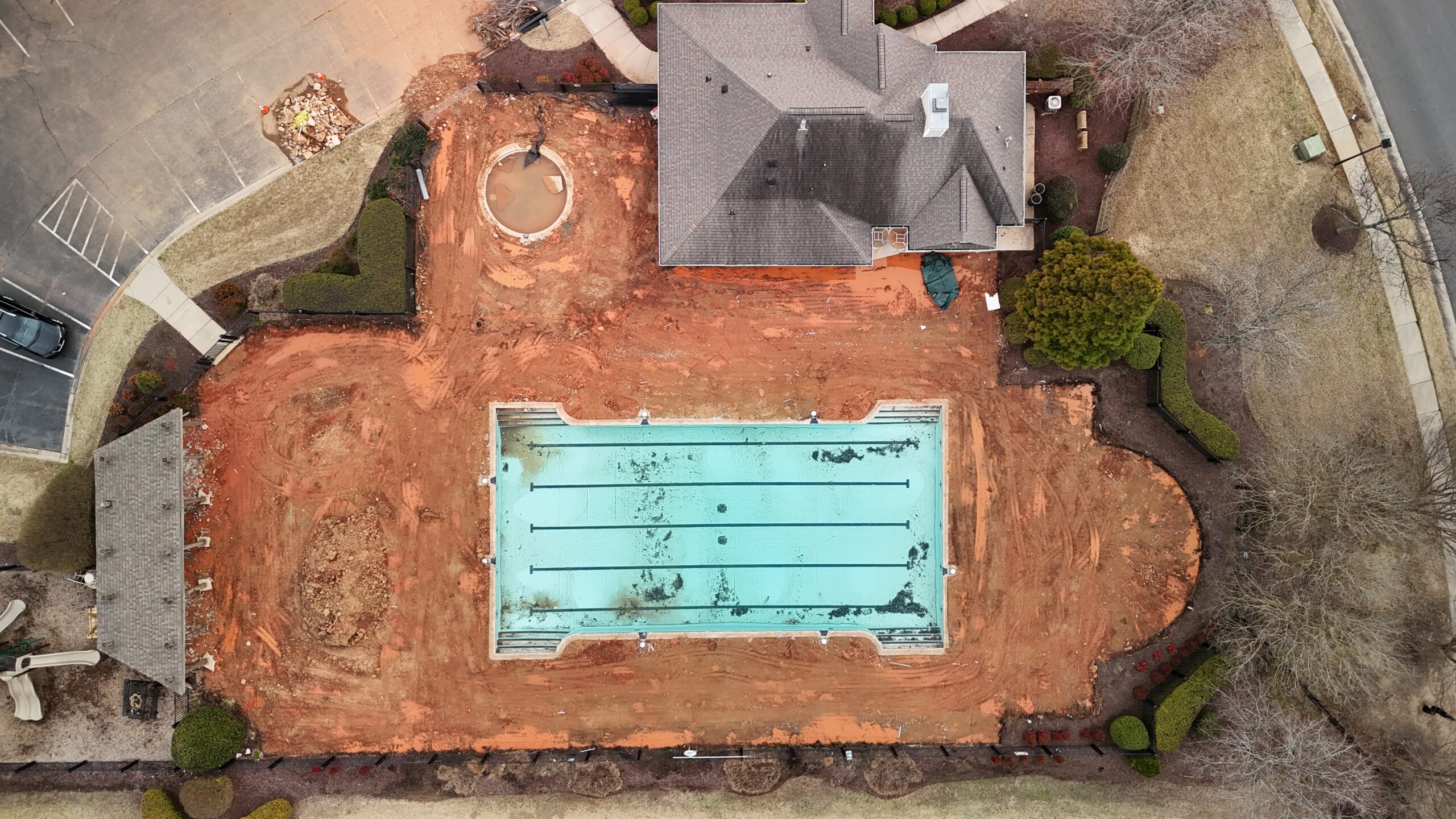 An overhead drone photo of a community pool surrounded by dirt. It is being remodeled.