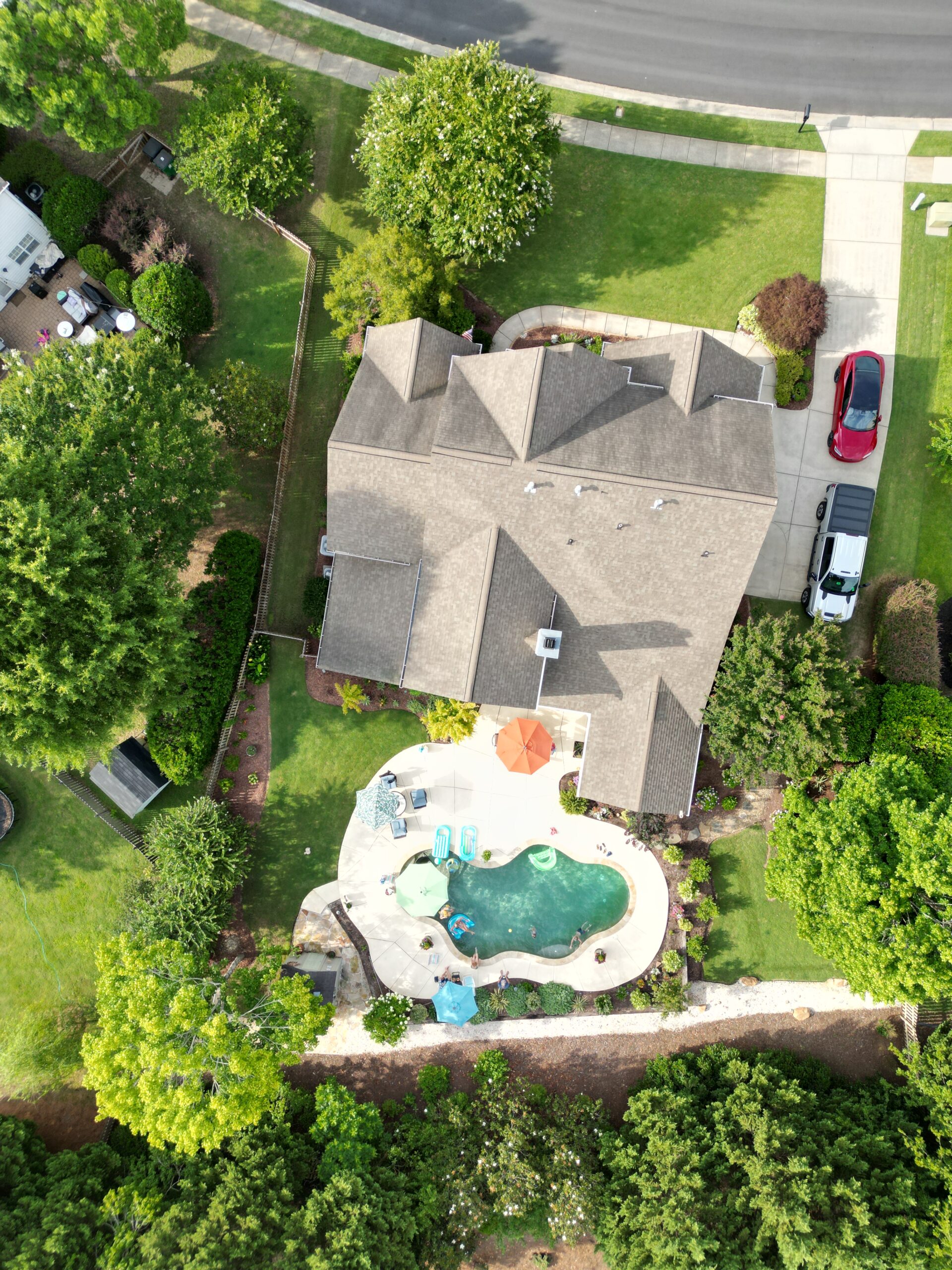 An overhead photo of a house with a pool in the backyard and a lush lawn.